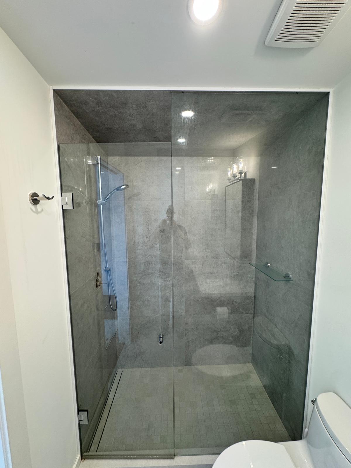Walk-in glass shower with large-format stone tile