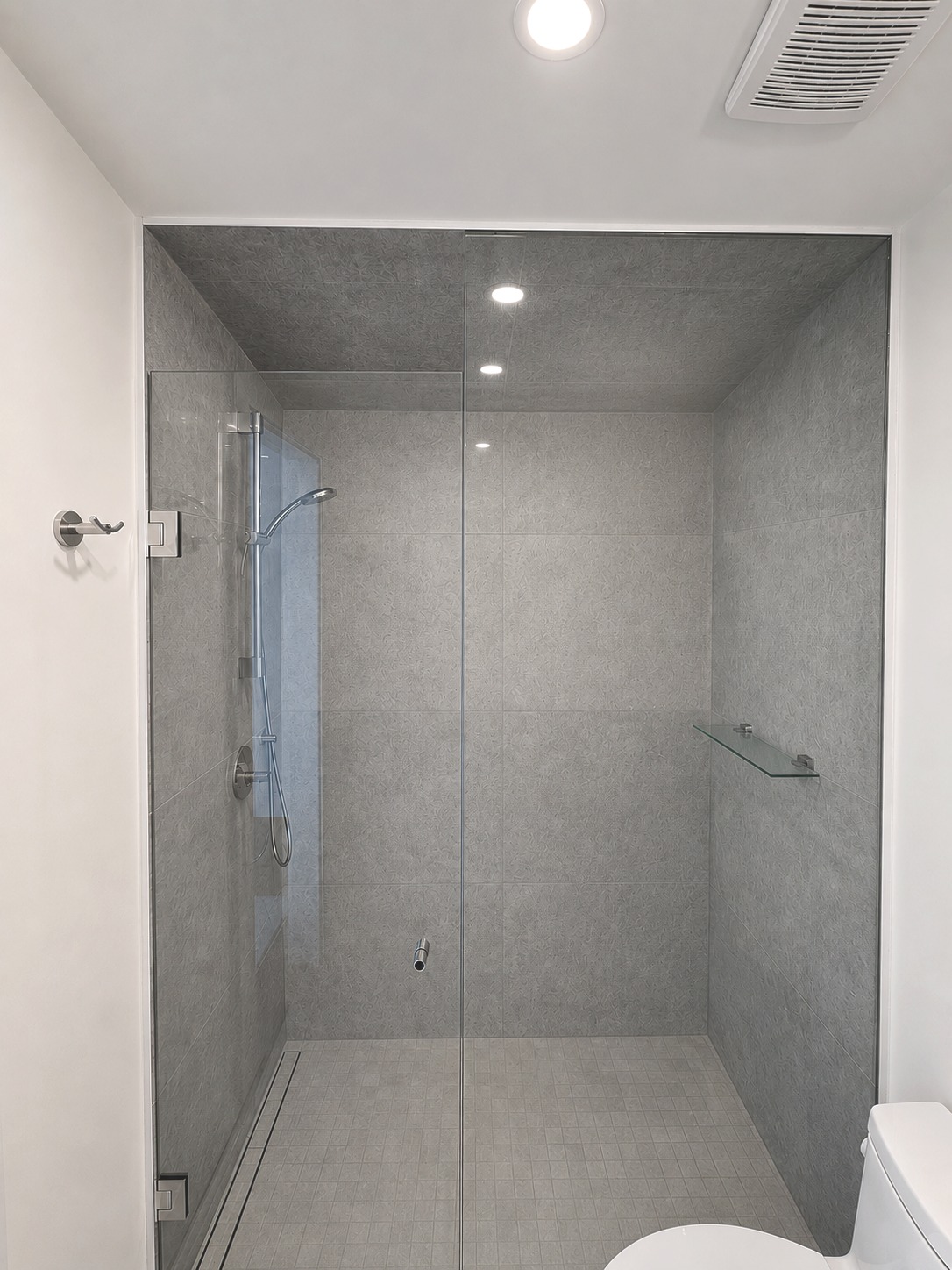 Walk-in glass shower with large-format stone tile