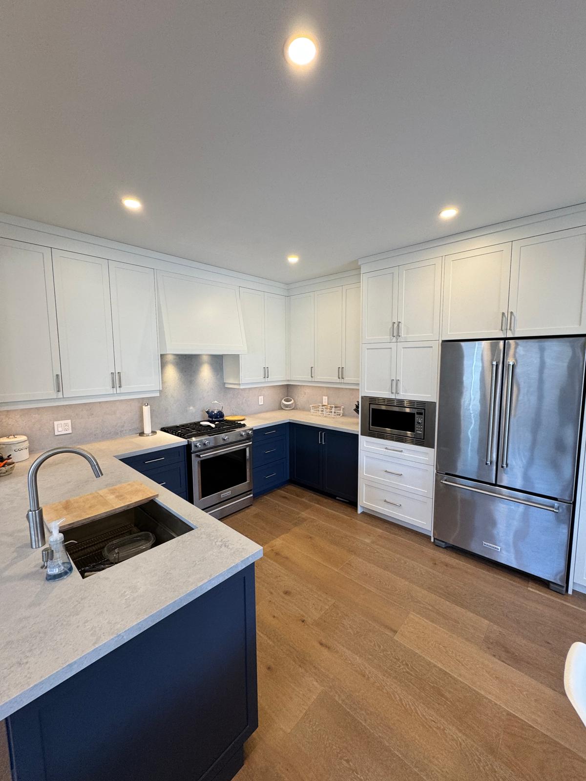 Open-concept kitchen, dining and living with navy island and shiplap walls
