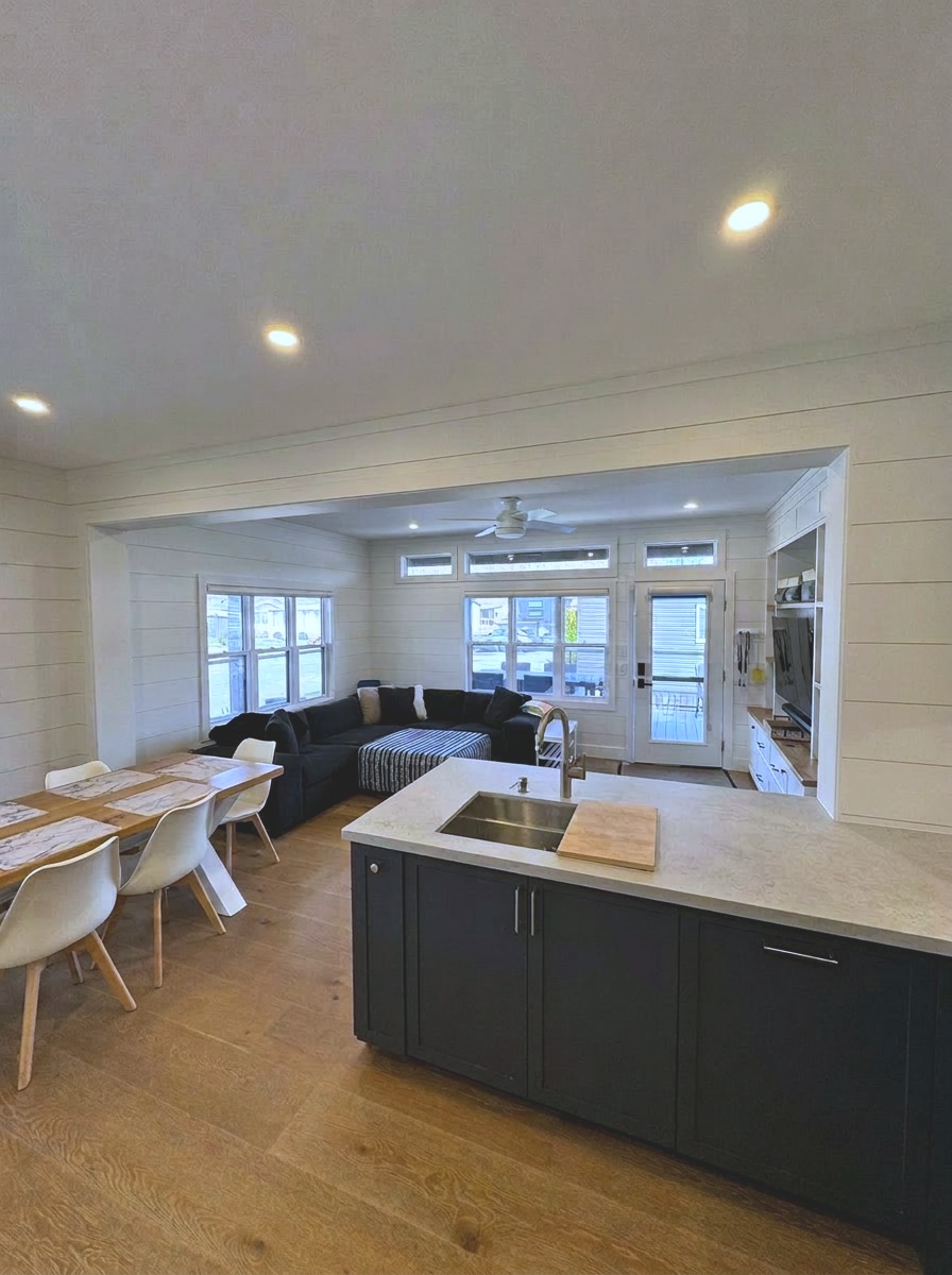 Open-concept living, dining and kitchen with navy island and walkout to wrap-around deck